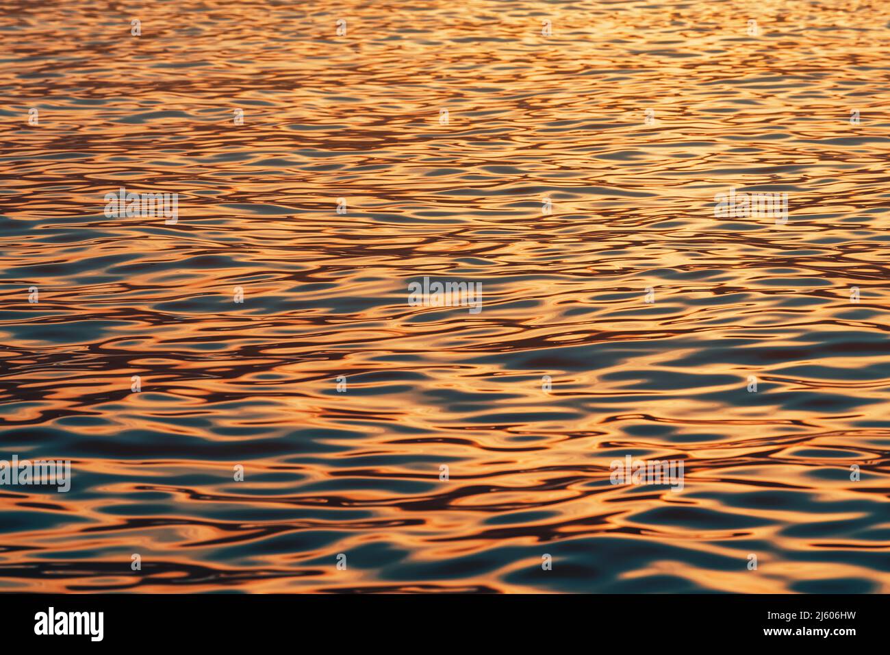 Geriffelte Oberfläche des blauen Meerwassers bei Sonnenuntergang, Orange- und Blautöne, selektiver Fokus Stockfoto