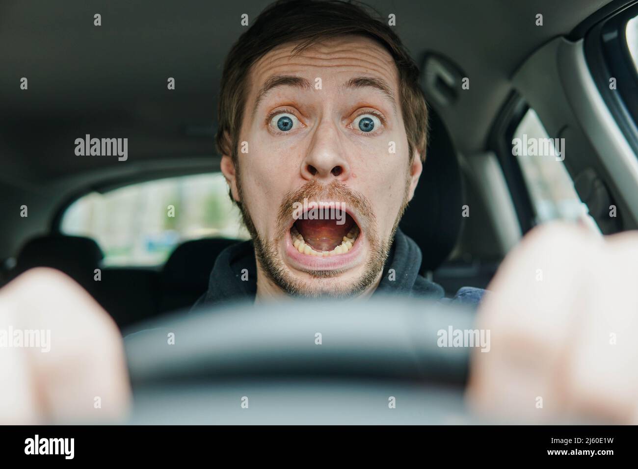 Nahaufnahme eines schockierten männlichen Fahrers mit überraschendem Gesicht und offenem Mund. Stockfoto