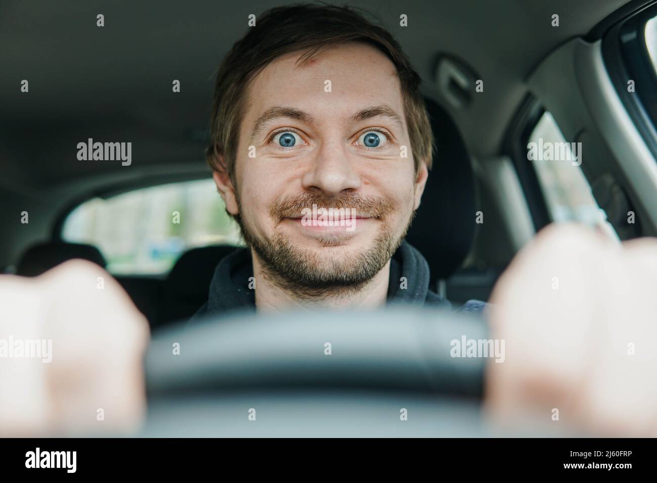 Nahaufnahme eines glücklichen, begeisterten Fahrer-Begginers am Steuer seines ersten Autos. Stockfoto