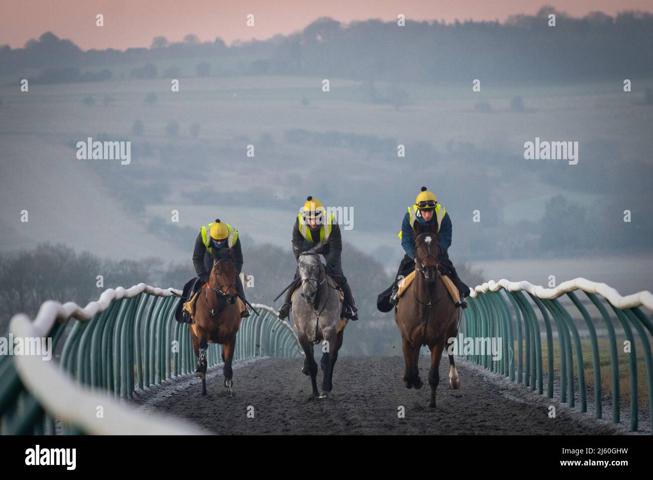 Rennpferde trainieren bei Sonnenaufgang in den Galops über dem Oberen Lambourn in den Berkshire Downs. April 2022 Stockfoto