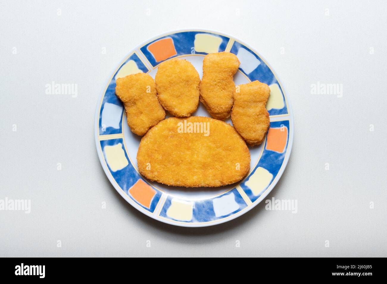 Ungekochte panierte halbfertige Schnitzel auf einem Teller in Form einer Hundepfote Fußabdruck Stockfoto