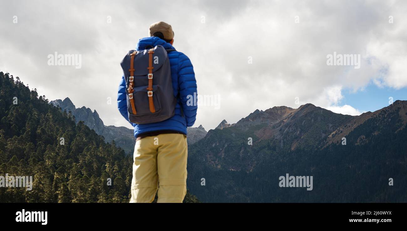 Rückansicht des asiatischen Reisenden mit Rucksack und Blick auf die Berge Stockfoto