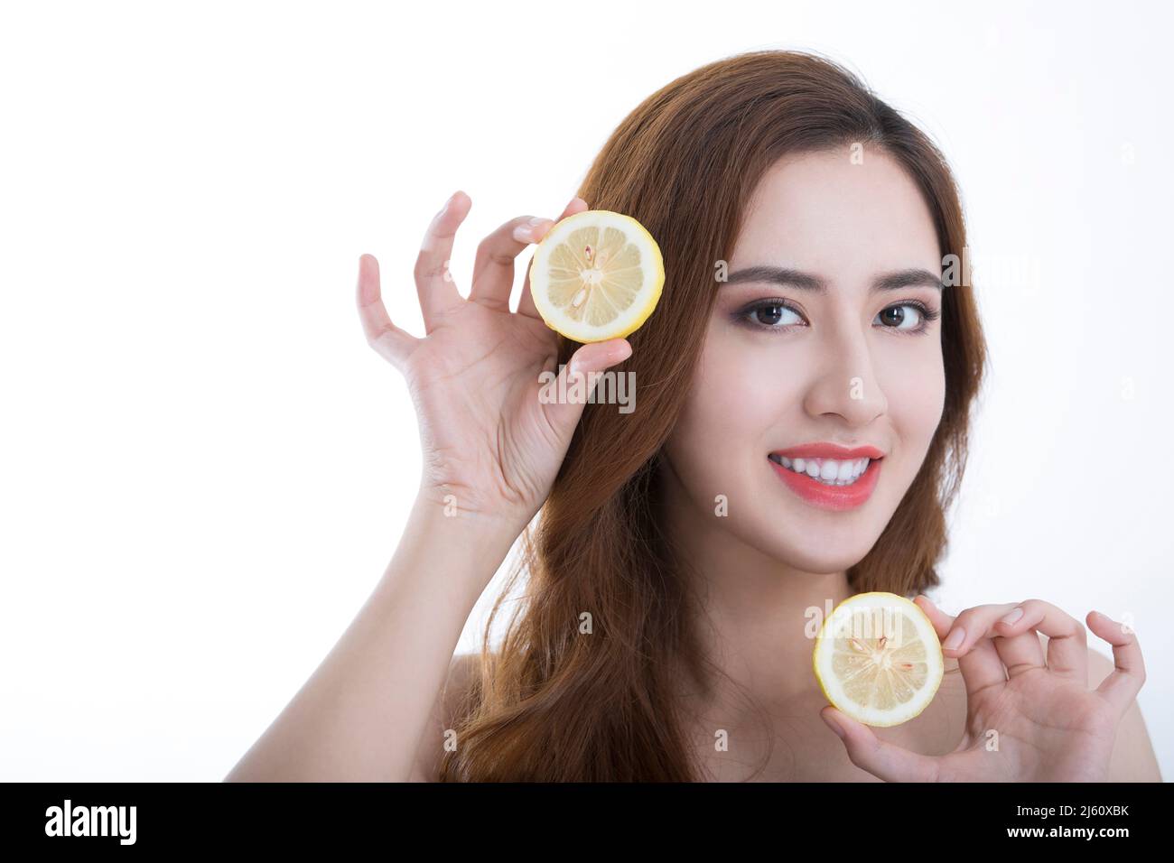 Hübsche junge Dame verspielt in Scheiben geschnittene Zitronen, auf weißem Hintergrund - Stock Foto Stockfoto