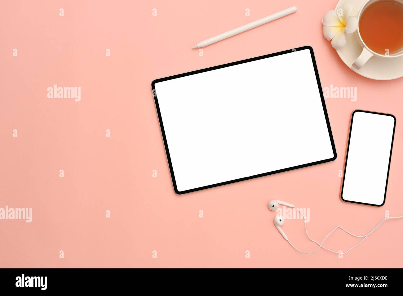 Rosa Arbeitsplatz Hintergrund mit digitalen Tablet und Smartphone weißen Bildschirm Mockup, eine Tasse Tee, Kopfhörer und Eingabestift. Draufsicht Stockfoto