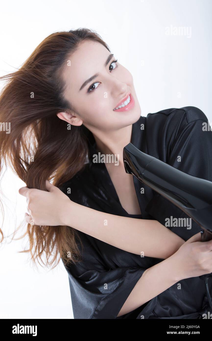Junge und schöne chinesische Frau mit einem Haartrockner, um Haare zu trocknen, auf weißem Hintergrund - Stock Foto Stockfoto