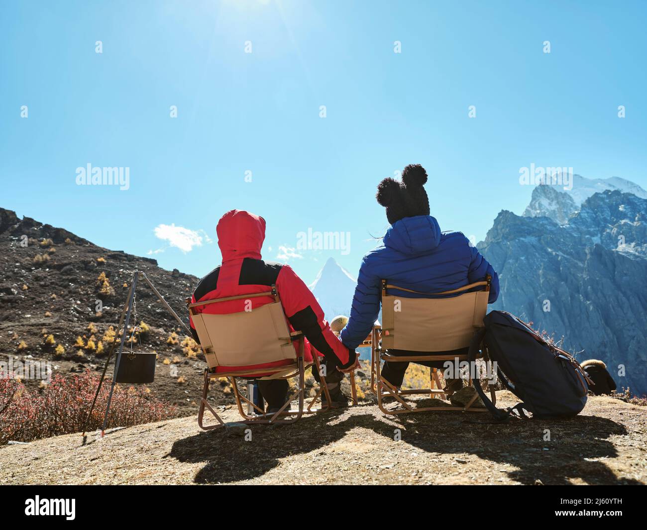 Rückansicht des asiatischen Paares, das auf Stühlen auf dem Berg sitzt und die Aussicht im yading Nationalpark, Bezirk daocheng, Provinz sichuan, china, betrachtet Stockfoto