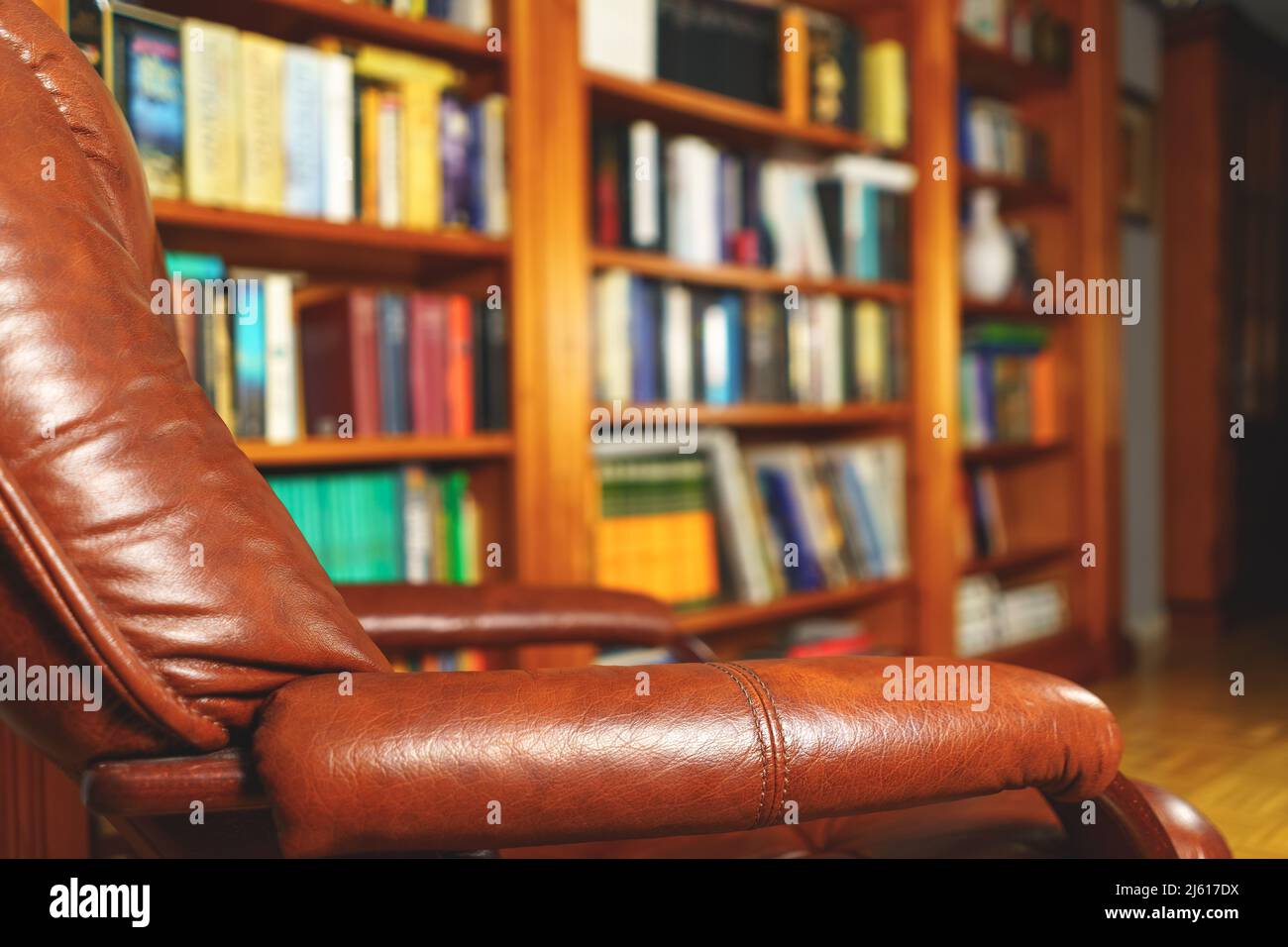 Entspannender Sessel in der Bibliothek mit mehreren Büchern zum Lesen an einem entspannten und komfortablen Ort. Stockfoto