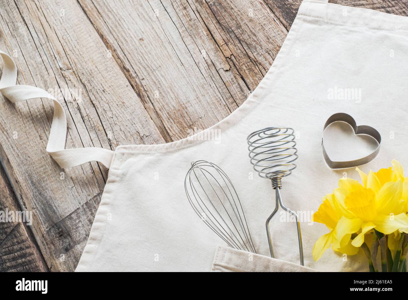 Close up Utensilien Backen Desserts mit Bouquet von frischen Narzissen auf der Schürze auf einem hölzernen Hintergrund. Flache Lage, Ansicht von oben. Hochwertige Fotos Stockfoto