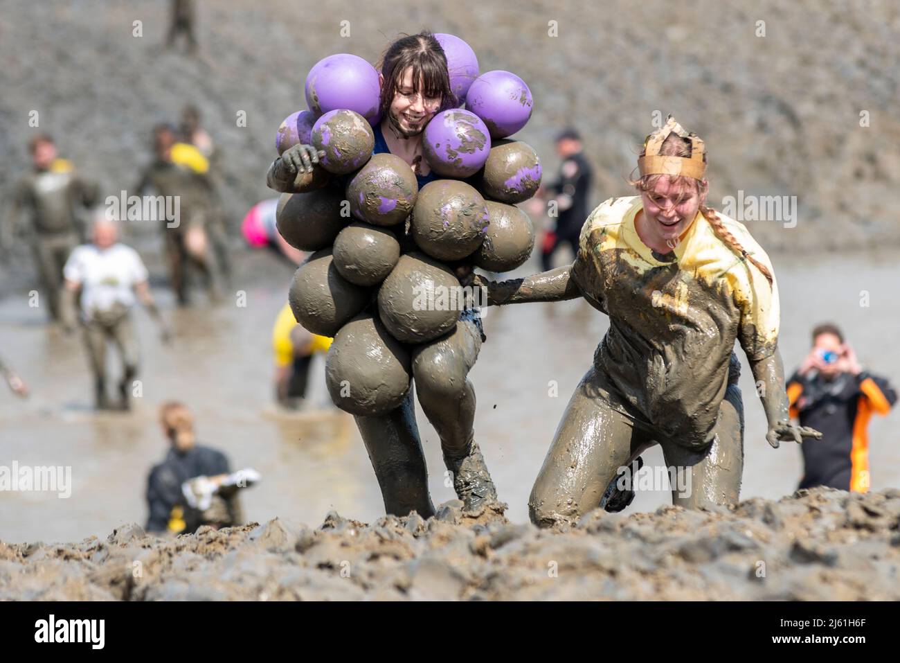 Emily Raymond und Lucy Raymond beim Maldon Mud Race 2022 auf dem River Blackwater, Essex, Großbritannien. Weibchen mit Schlamm bedeckt, in Kostümen Stockfoto