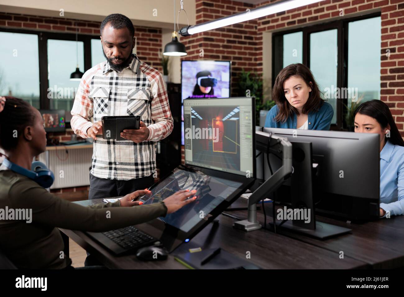 Entwickler der Spielebranche mit mehreren Displays auf dem Schreibtisch, die auf Level-Design und -Umgebung arbeiten. Mitarbeiter der Produktionsabteilung im Bürobereich entwickeln Videogame-Technologie. Stockfoto