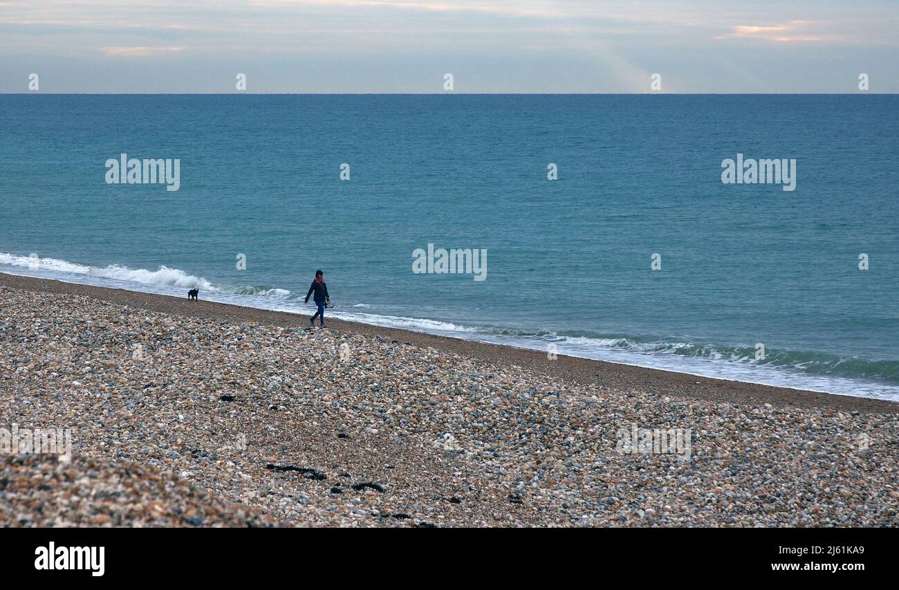 Eine kleine Figur sah den Hund in der Küstenlandschaft von Aldwick, an der Südküste Großbritanniens, an einem frühen Morgen im April 2022 spazieren gehen. Stockfoto