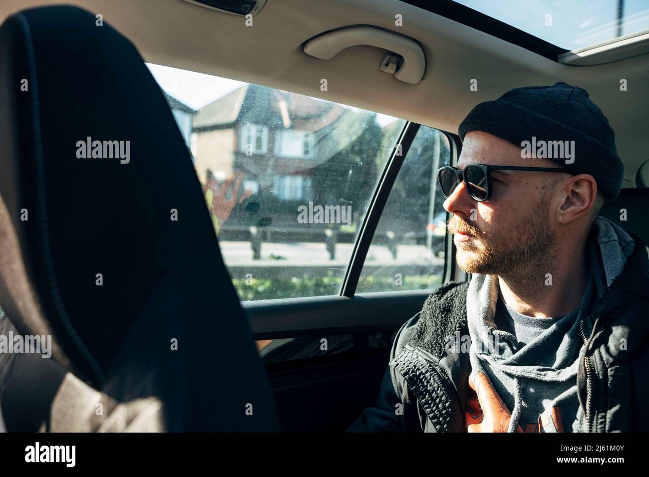 Junger Mann mit Sonnenbrille sitzt im Auto Stockfoto