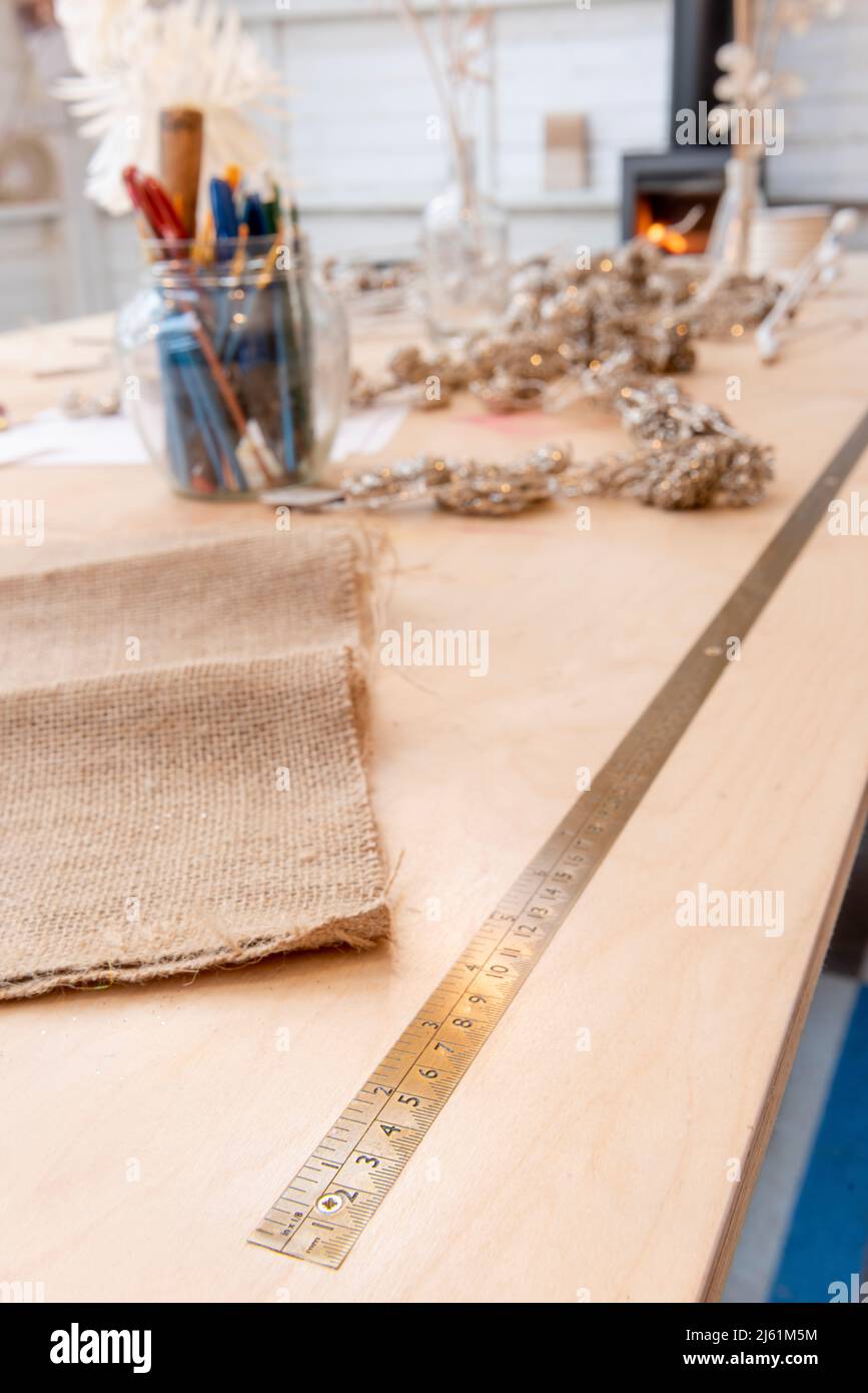 Arbeitstisch aus Holz mit eingestelltem Messinglineal mit verzogenem Holzbrenner in der Ferne. Stockfoto