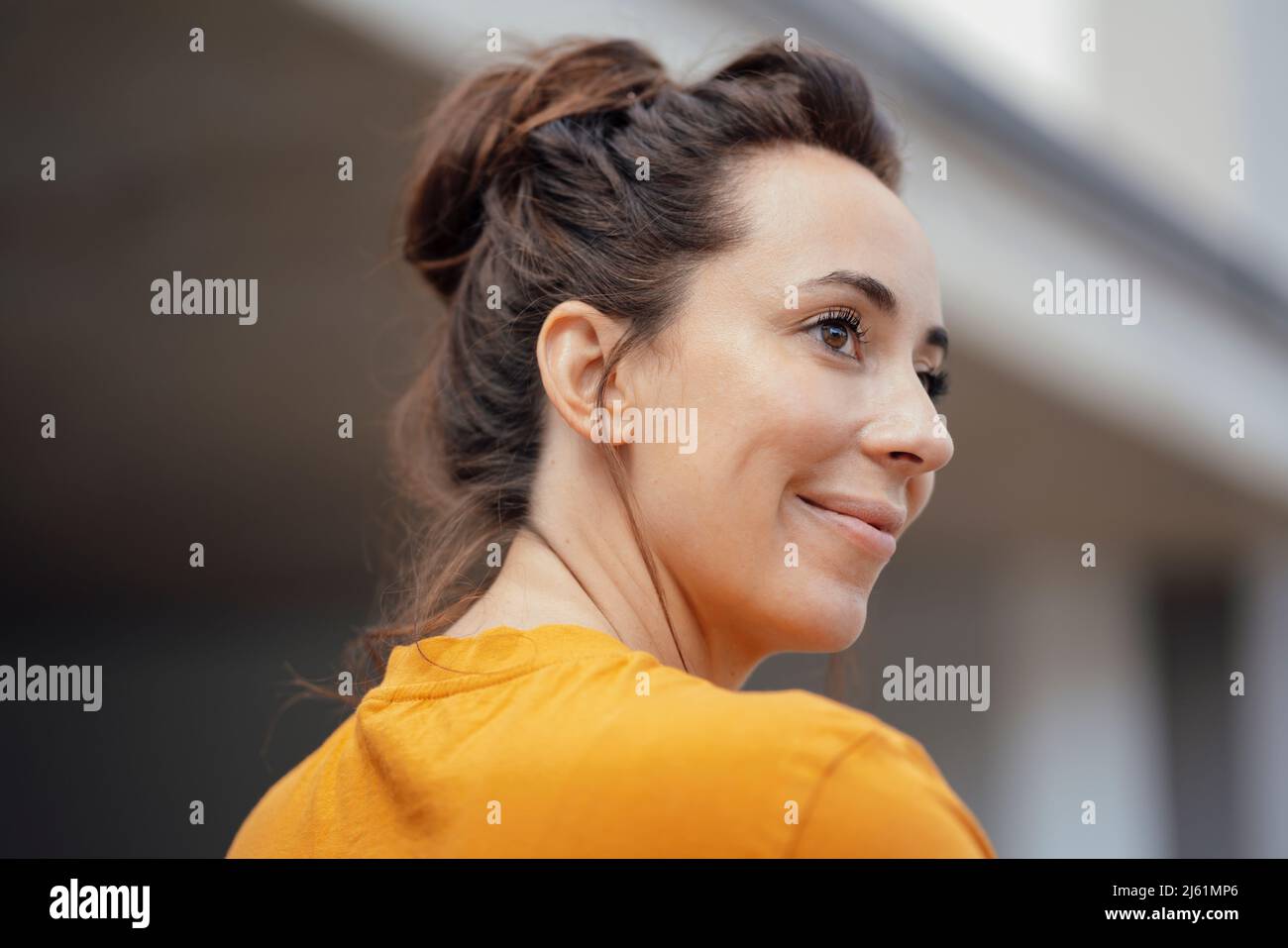 Lächelnde, schöne Frau mit braunen Haaren, die über die Schulter schauen Stockfoto