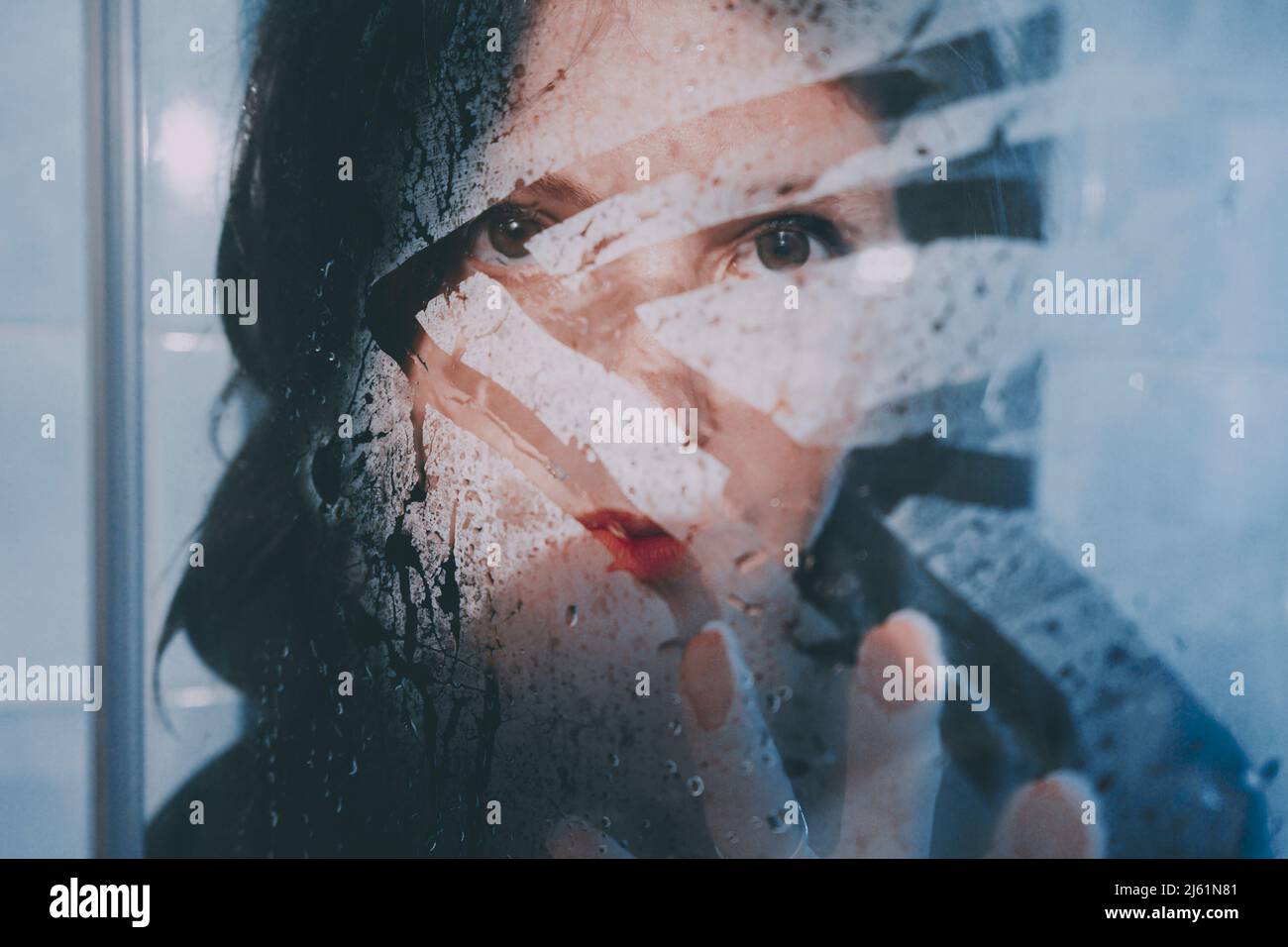 Frau hinter nassem transparentem Glas Stockfoto