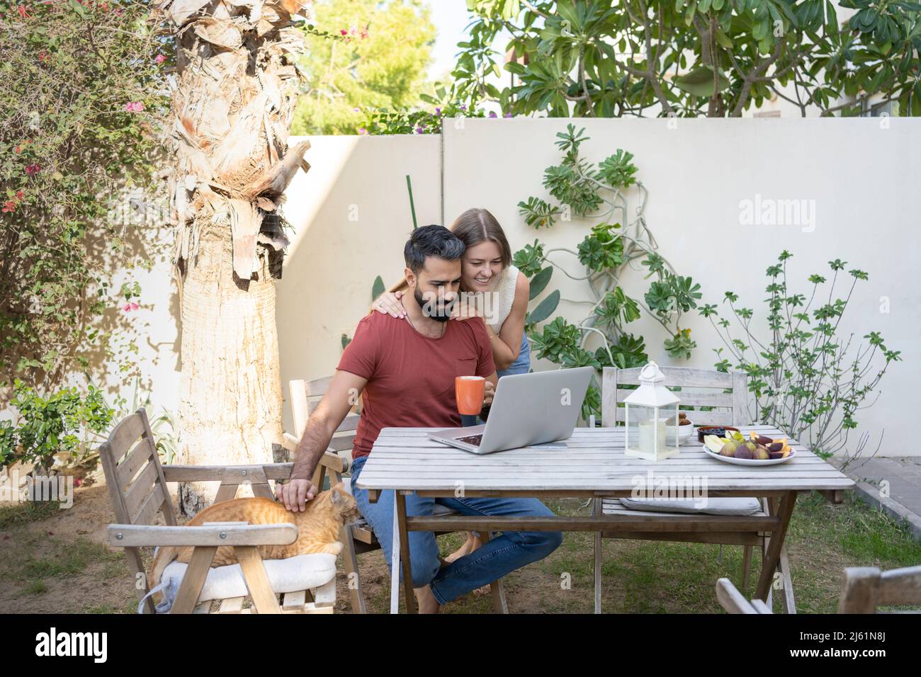 Mann mit Laptop und Frau hinter dem Hinterhof Stockfoto