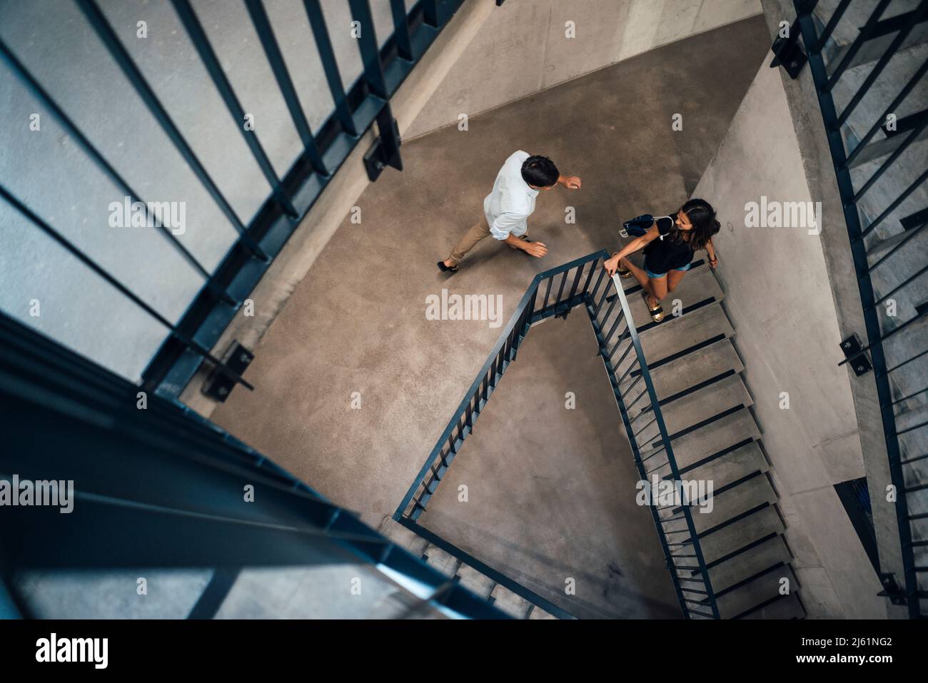 Junger Mann, der hinter der Freundin herläuft und die Stufen hinuntergeht Stockfoto