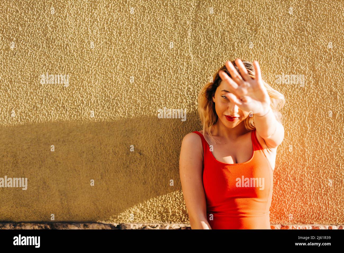 Junge Frau tut Stop-Geste vor der Wand Stockfoto