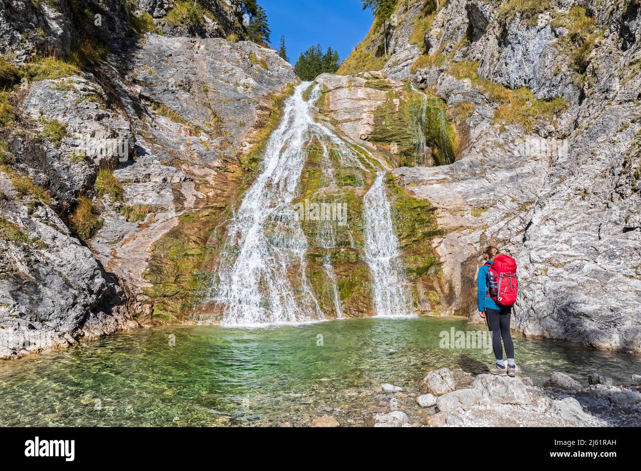 Weibliche Wandererin bewundert den Glasbach Wasserfall in den bayerischen Voralpen Stockfoto