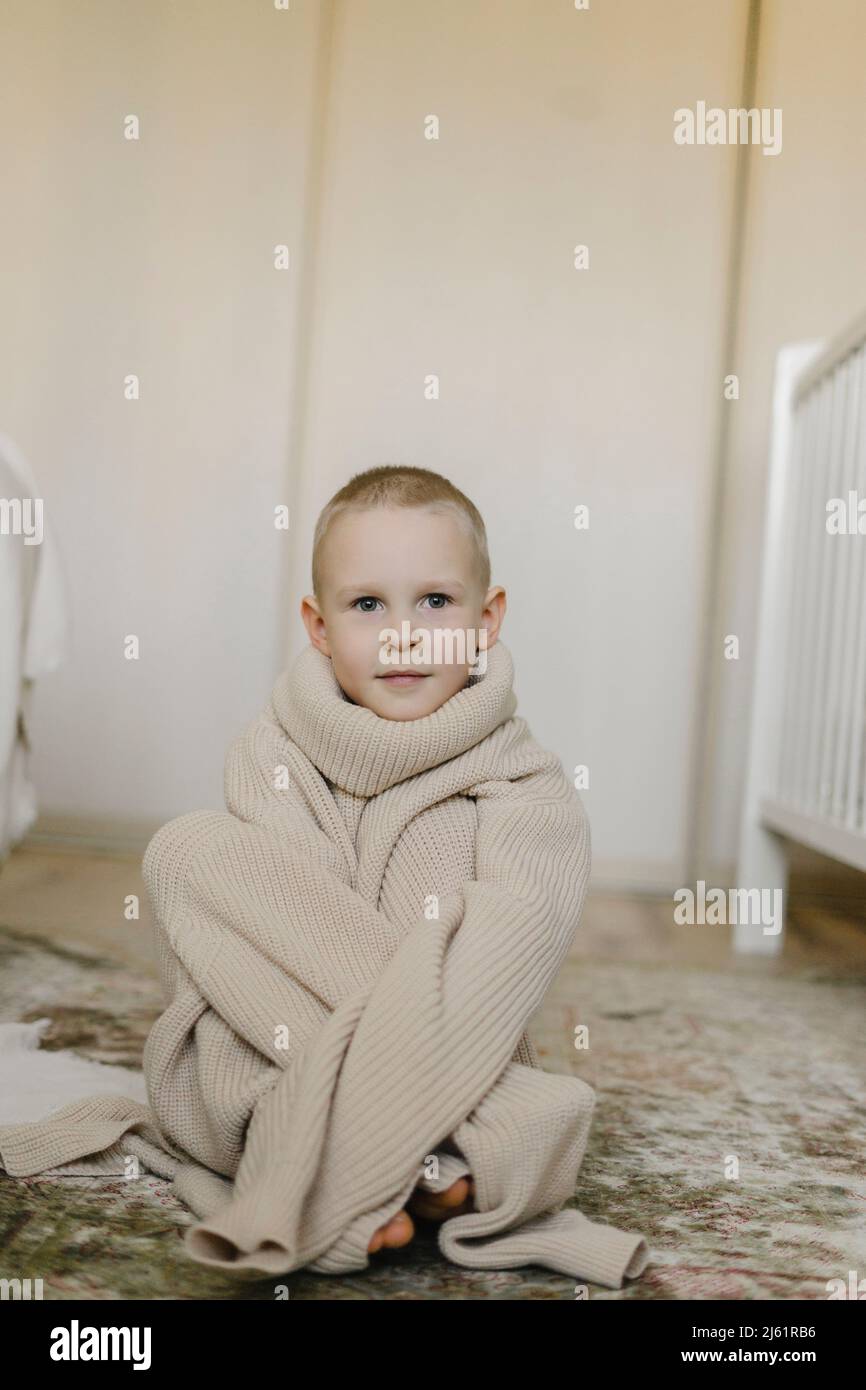 Junge trägt übergroßen Pullover zu Hause Stockfoto