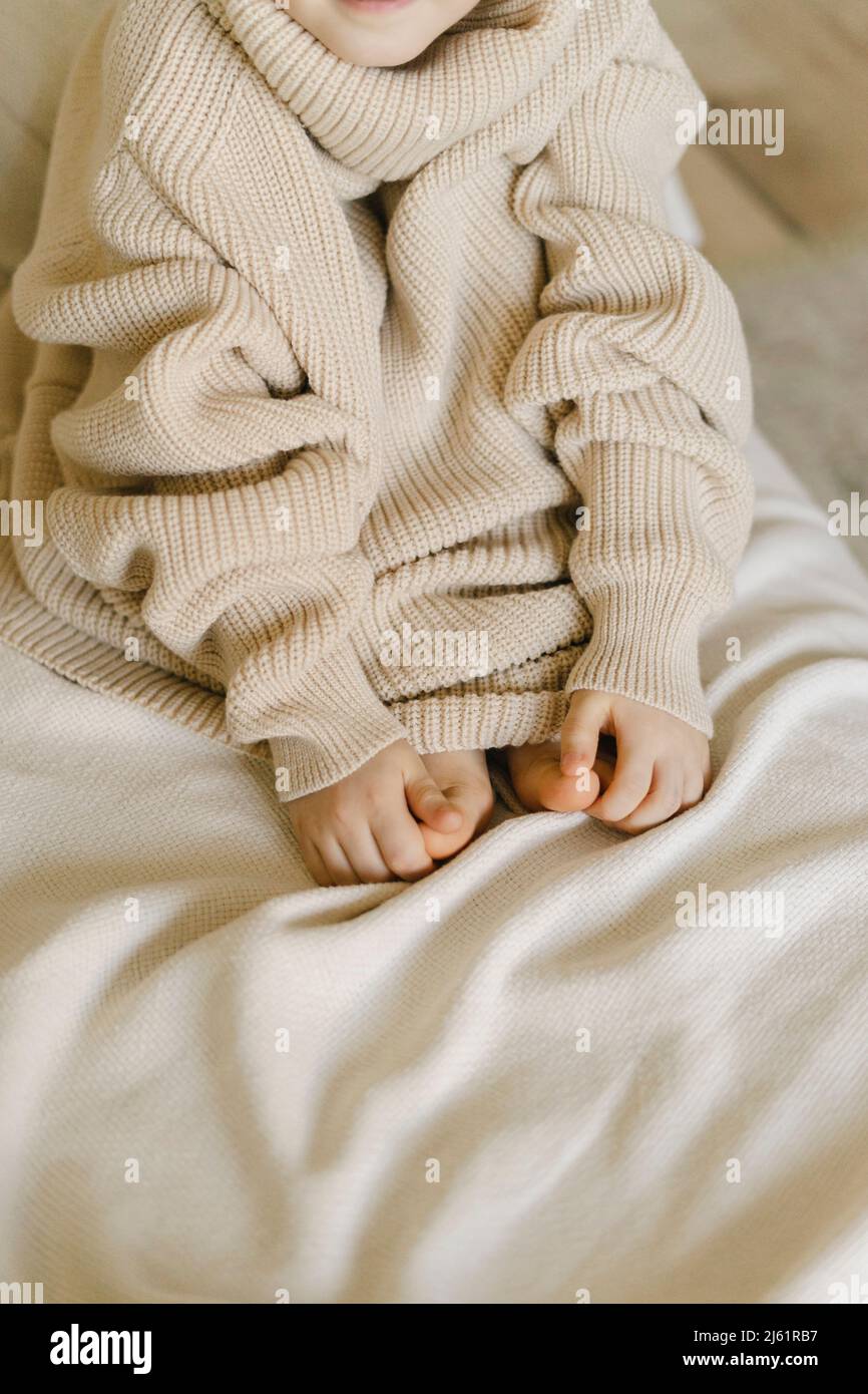 Junge trägt zu Hause einen kuscheligen übergroßen Pullover Stockfoto
