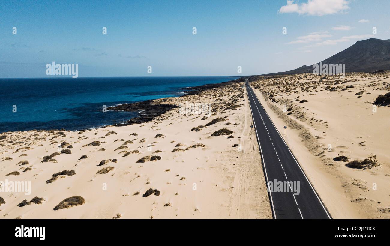 Spanien, Fuerteventura, Luftaufnahme der Autobahn, die sich durch die sandige Landschaft des Naturparks Corralejo erstreckt Stockfoto