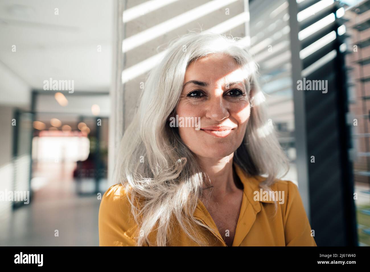 Lächelnde Frau, die vor der Säule am Arbeitsplatz steht Stockfoto