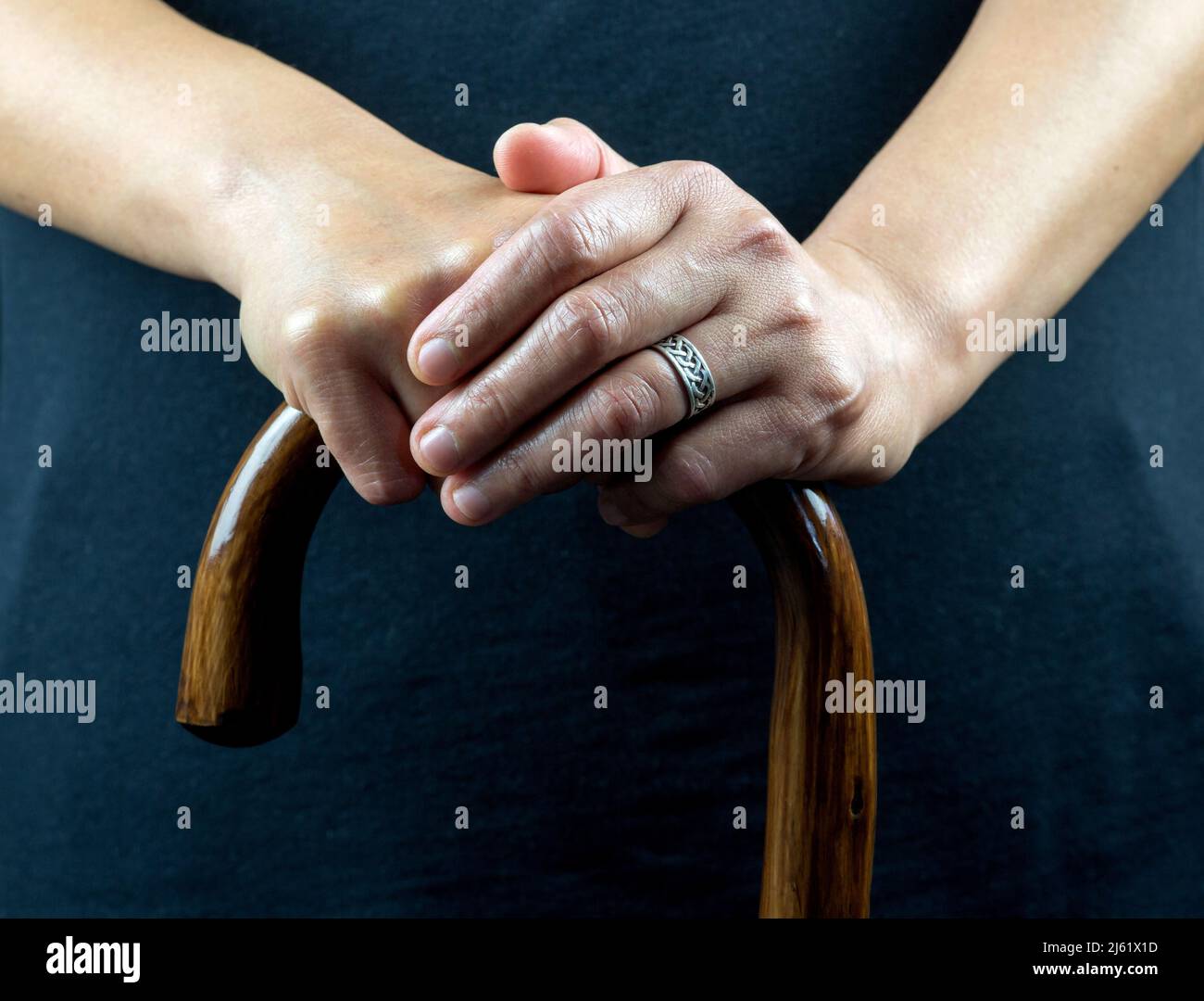 Hände einer älteren Dame auf einem hölzernen Spazierstock Stockfoto