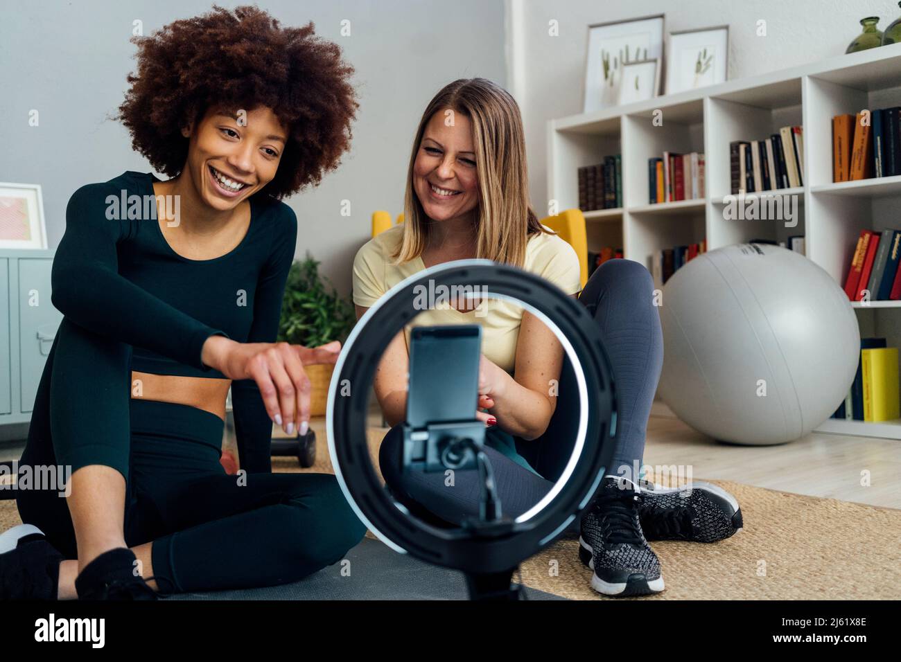 Glücklicher junger Influencer mit Freund vlogging im Wohnzimmer zu Hause Stockfoto