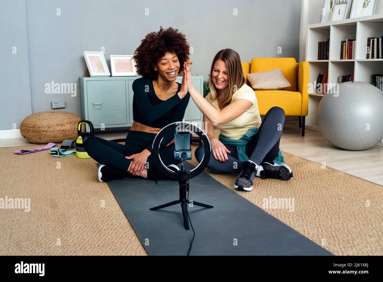 Glückliche Influencer geben sich im Wohnzimmer zu Hause hohe fünf beim Vlogging Stockfoto