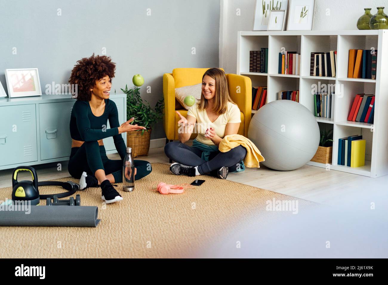 Glückliche Frauen werfen Äpfel sitzen im Wohnzimmer zu Hause Stockfoto
