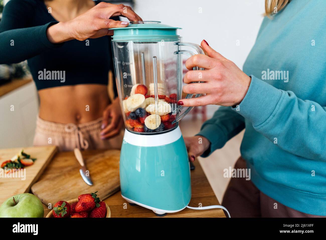 Freunde mischen Früchte im Mixer zu Hause Stockfoto
