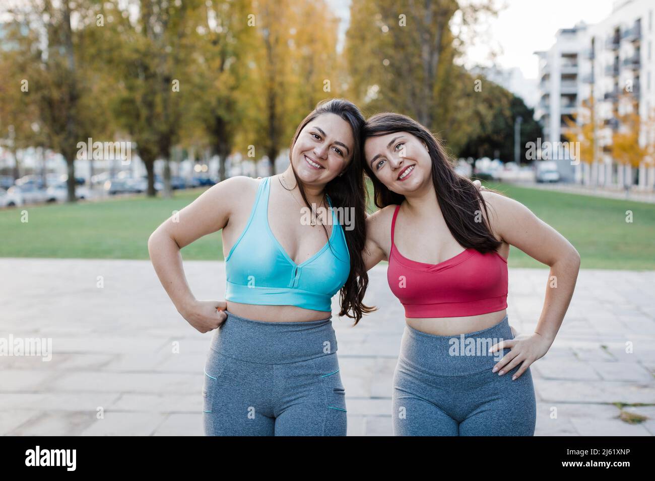 Lächelnde Frauen im Sport-BH stehen im öffentlichen Park Stockfoto