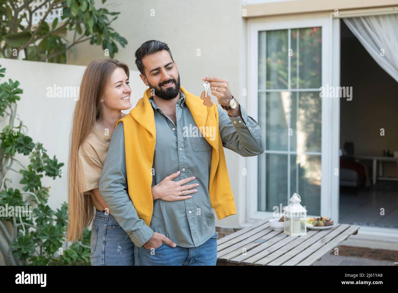 Heterosexuelles Paar mit Hausschlüssel im Garten Stockfoto