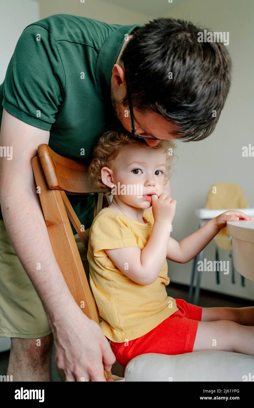 Mann küsst Tochter auf dem Kopf von hinten in der Küche zu Hause Stockfoto