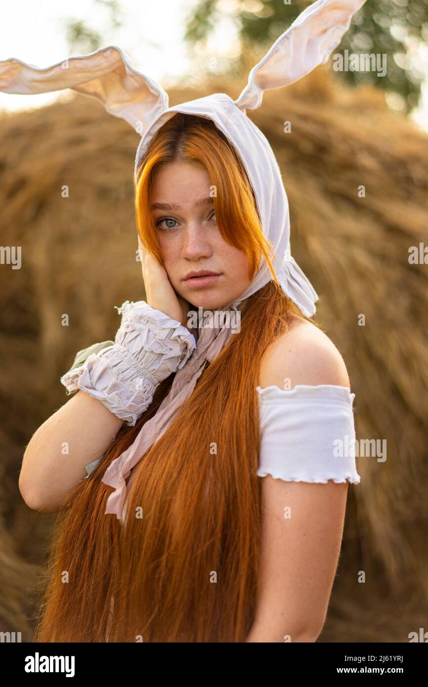 Junge Frau mit Hasenkostüm-Ohren vor Heuballen Stockfoto