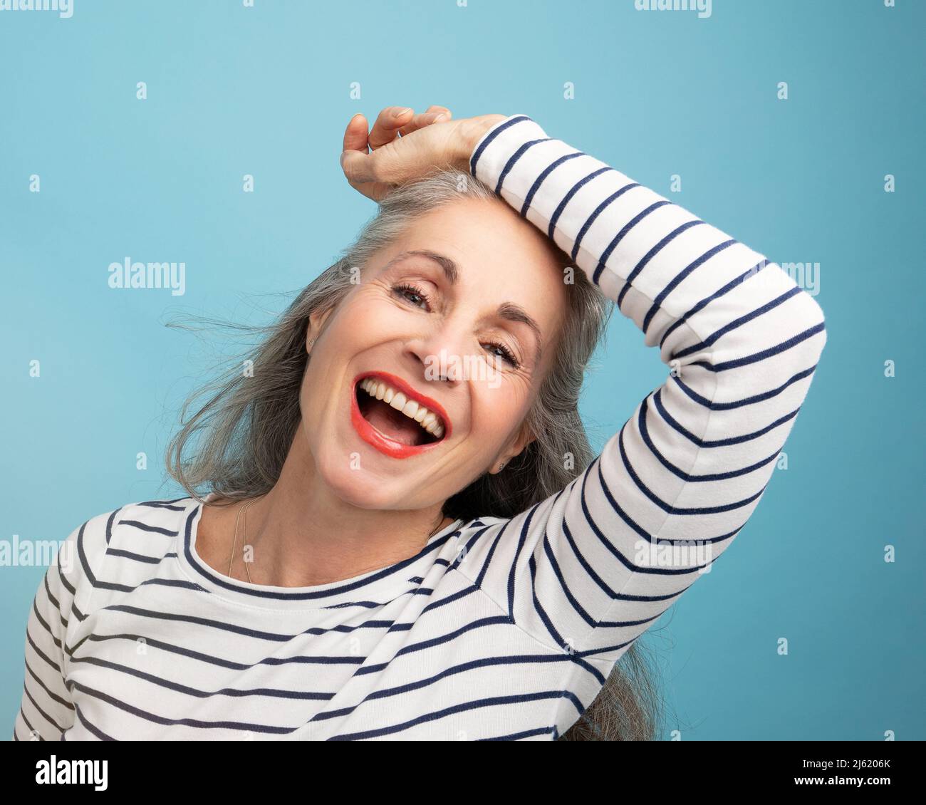 Glückliche Frau mit der Hand auf dem Kopf vor blauem Hintergrund Stockfoto