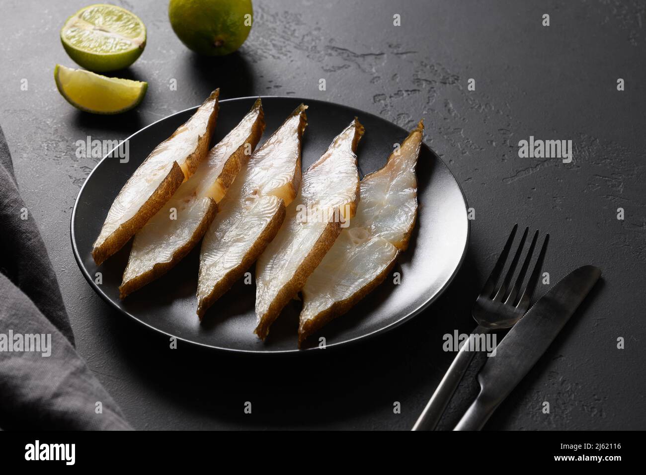 Köstliche geräucherte Heilbutt-Scheiben mit Limettenhintergrund serviert. Blick von oben. Speicherplatz kopieren. Stockfoto