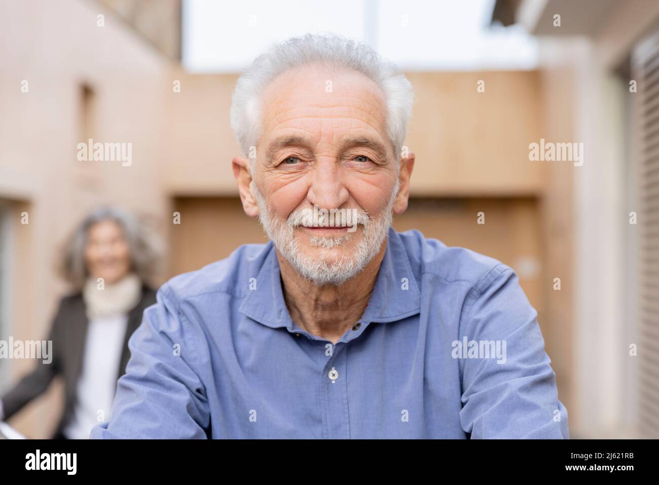 Lächelnder älterer Mann mit weißen Haaren vor der Frau Stockfoto
