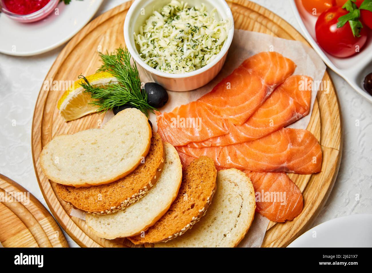 Leicht gesalzener Lachs mit Käse und Brotscheiben auf einem Holzbrett Stockfoto