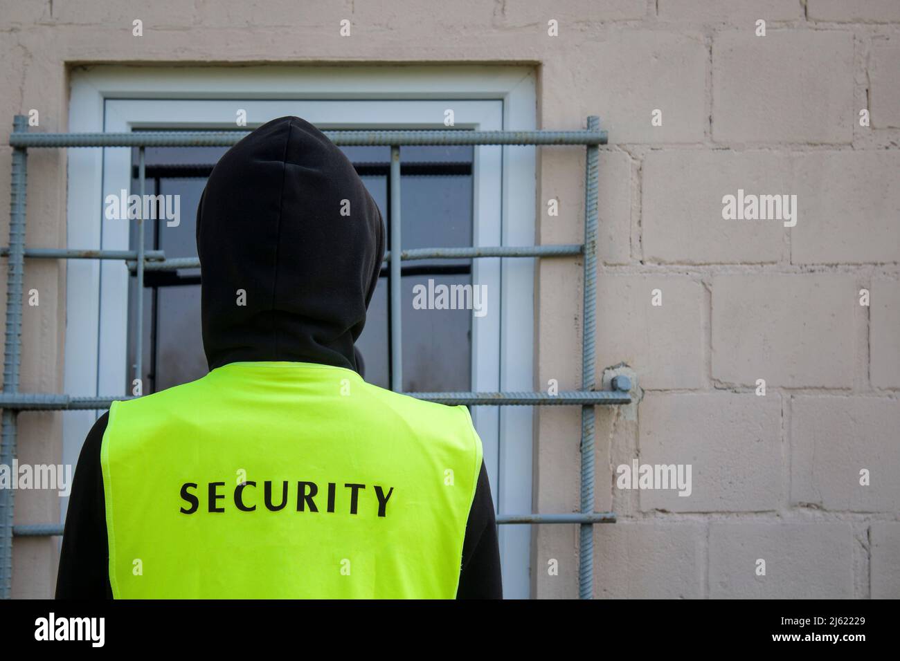 Sicherheitsbeamter in einer gelben Weste vor dem versperrten Fenster Stockfoto