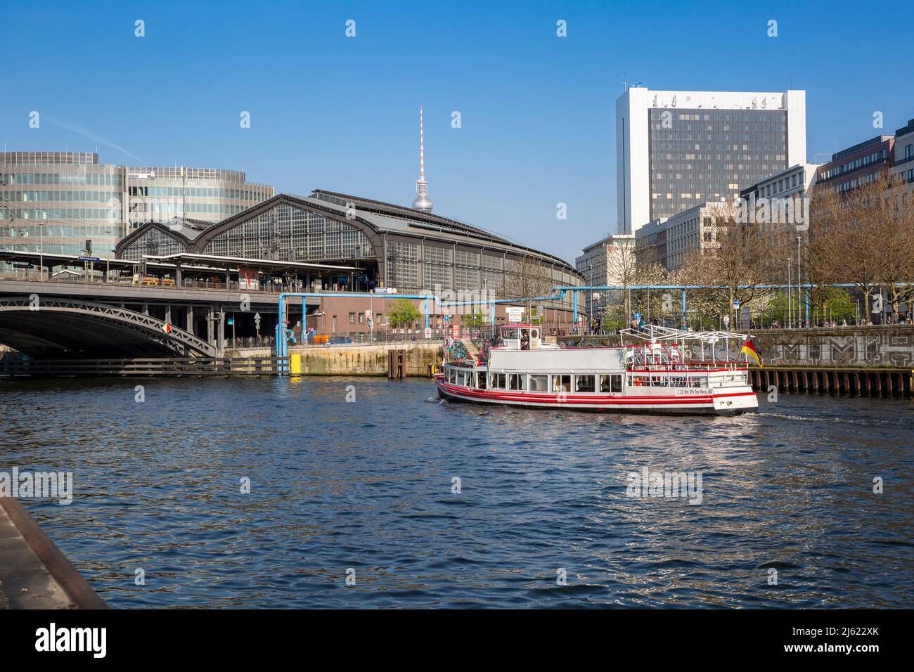 Deutschland, Berlin, Tourboot, das entlang der Spree segelt, mit dem Bahnhof Berlin Friedrichstraße und dem Fernsehturm Berlin im Hintergrund Stockfoto