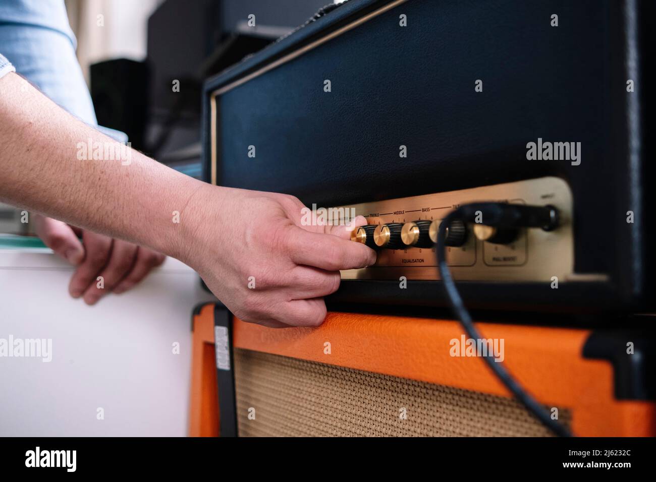 Hände eines Mannes, der Verstärker im Heimstudio verwendet Stockfoto