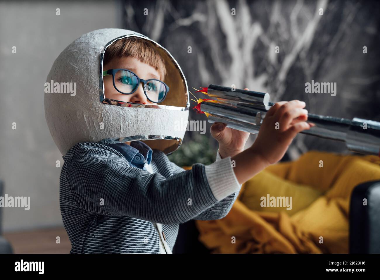 Junge trägt Weltraumhelm spielen mit Spielzeug Rakete zu Hause Stockfoto