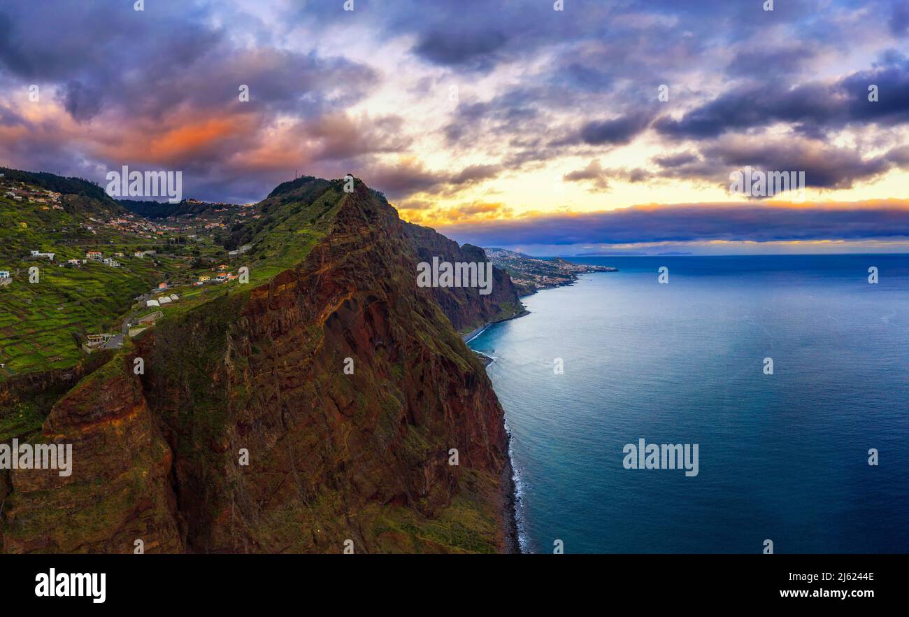 Sonnenuntergang über den Klippen der Insel Madeira mit der Stadt Funchal im Hintergrund Stockfoto