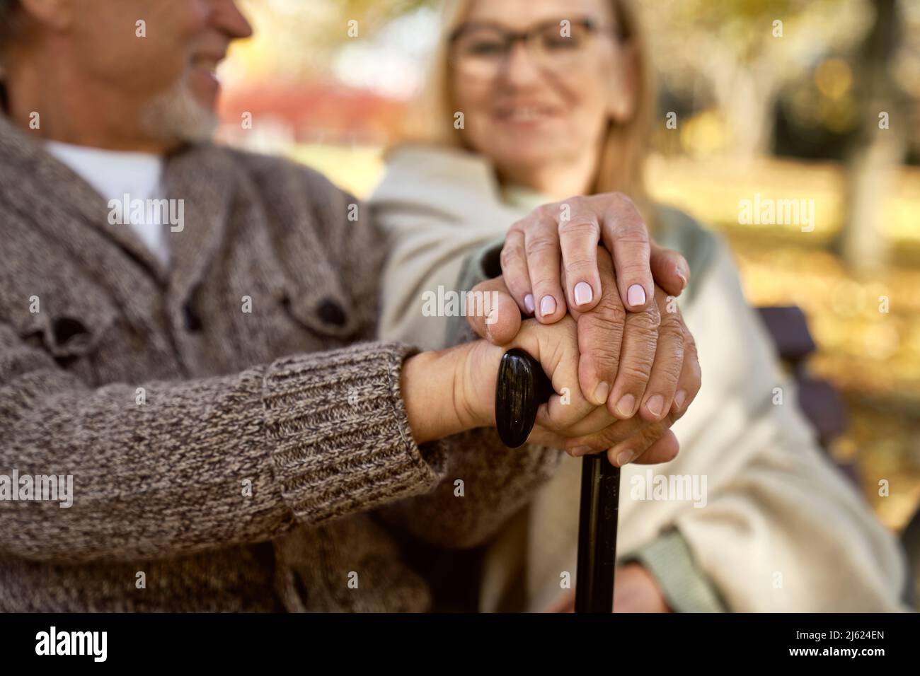 Seniorenpaar mit Spazierstock sitzt zusammen Stockfoto
