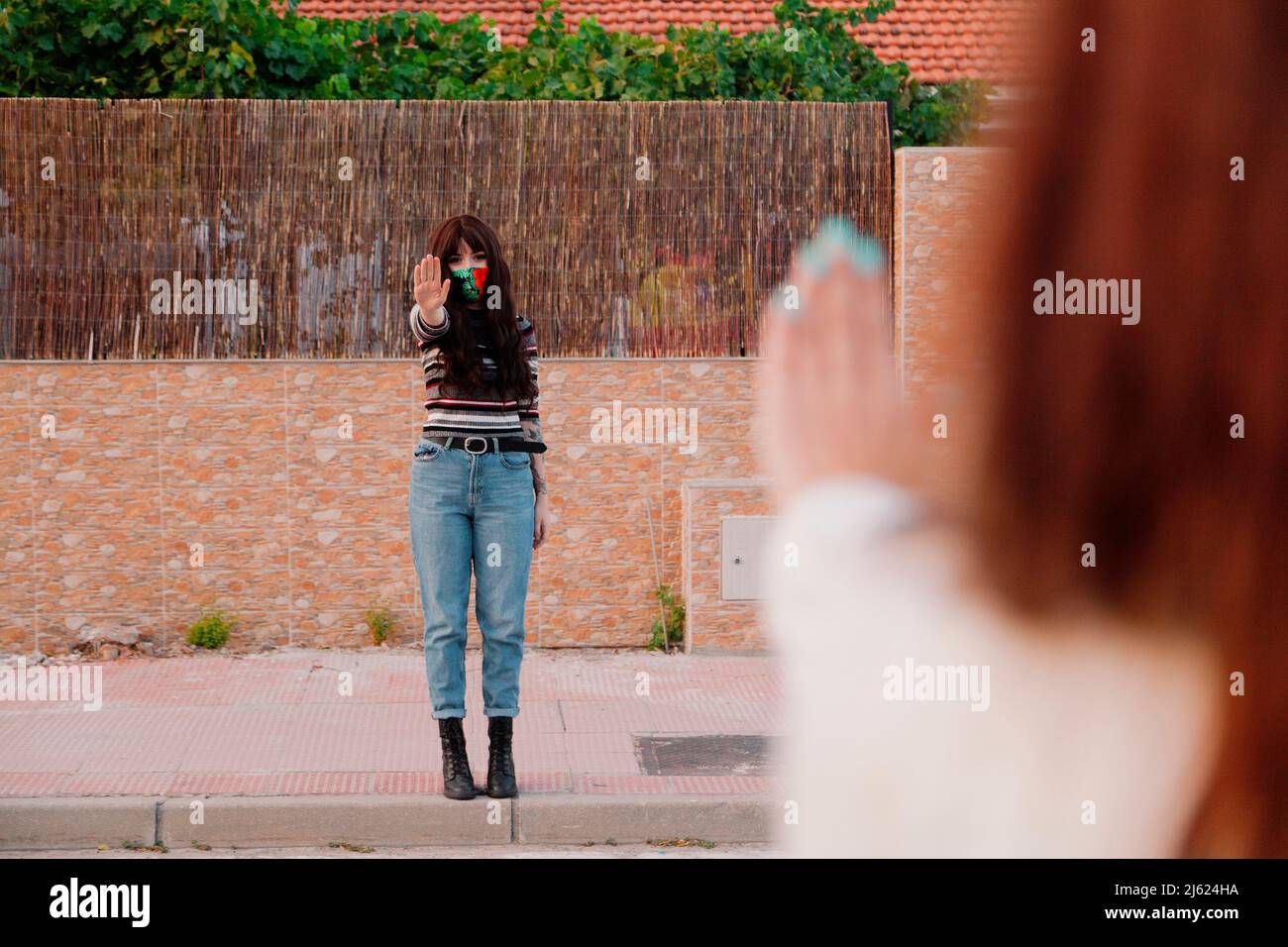 Frau trägt Gesichtsmaske zeigt Stop-Geste an Freund Stockfoto