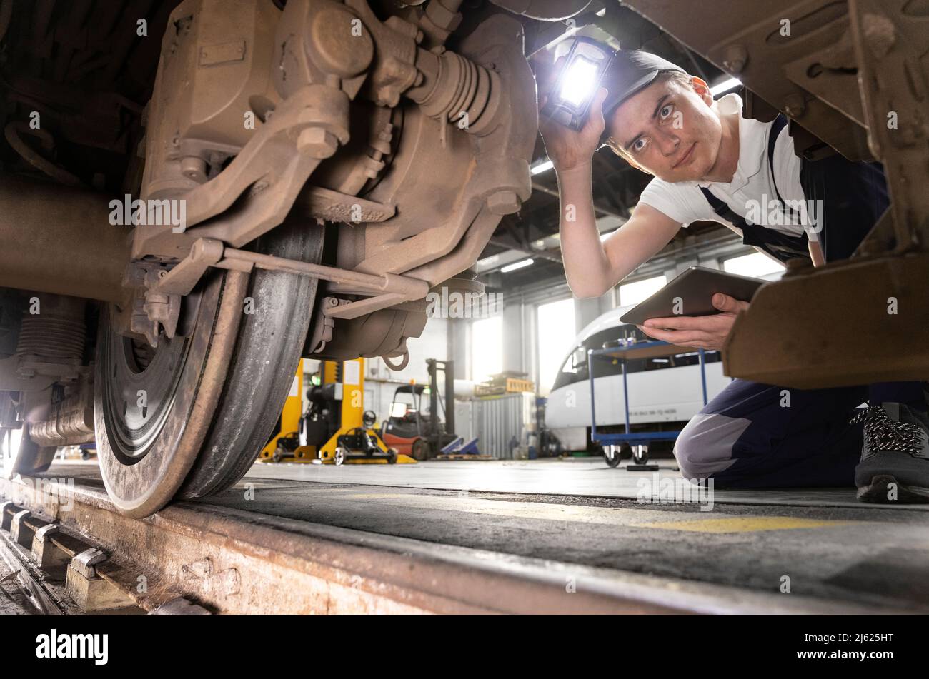 Junge Auszubildende mit Tablet-PC, die das Monorail-Rad im Werk untersuchen Stockfoto