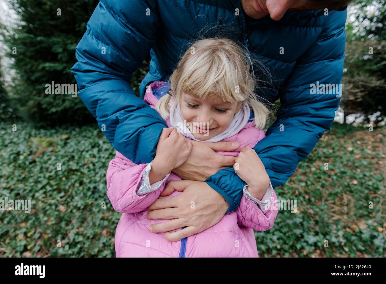 Lächelnde Tochter, die Spaß mit dem Vater im Freien hat Stockfoto