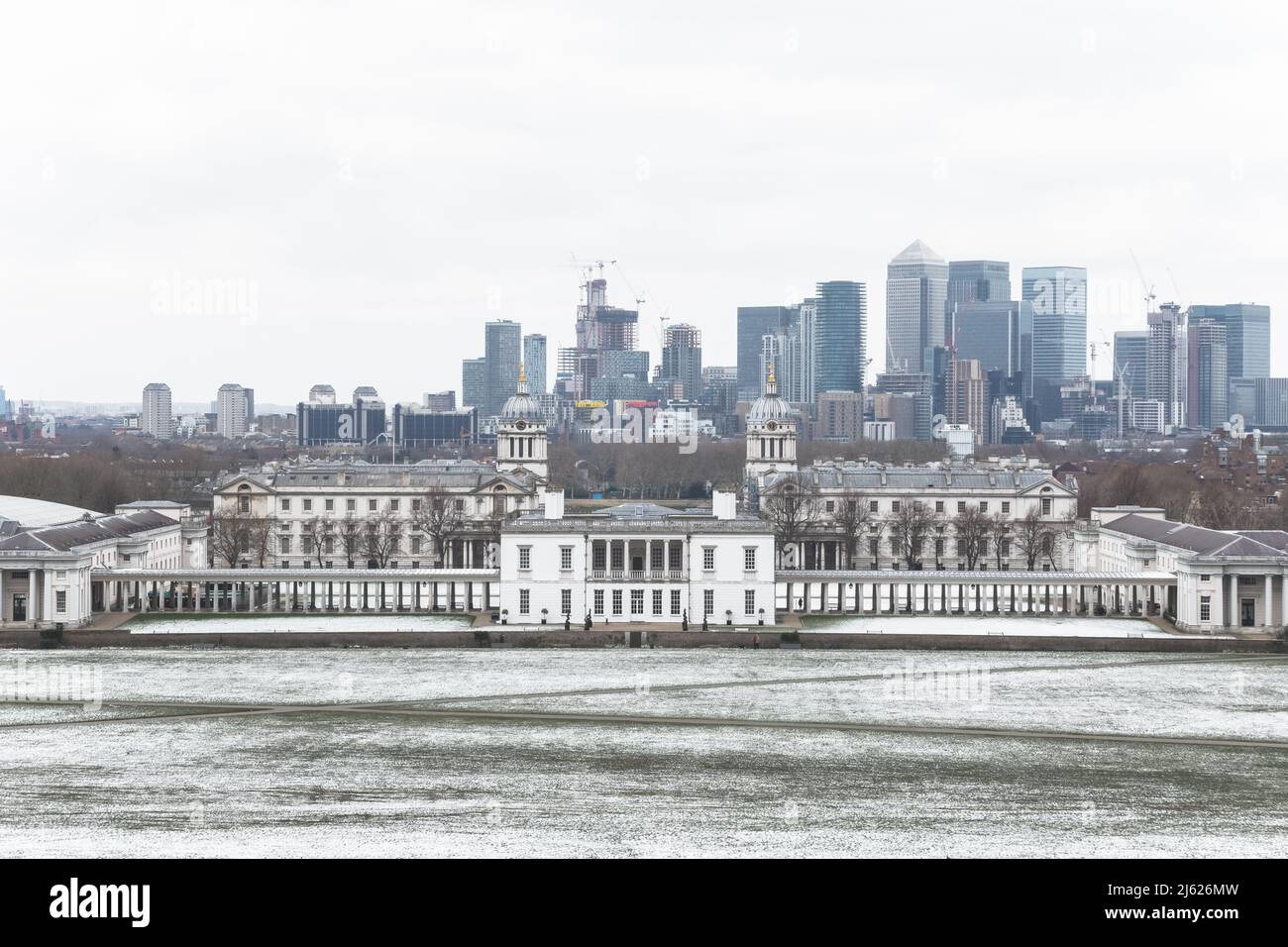 Blick auf das Queens House und Canary Wharf vom Greenwich Park in London im Winterschnee Stockfoto